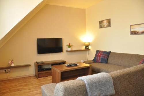 sala de estar con sofá y TV de pantalla plana en Ursprung Apartments, en Rostock
