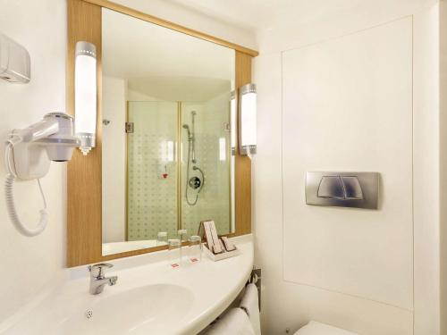 a white bathroom with a sink and a shower at ibis Yogyakarta Adi Sucipto in Yogyakarta