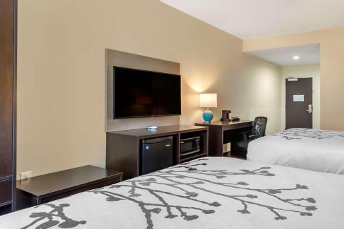 a hotel room with two beds and a flat screen tv at Sleep Inn & Suites in Waller