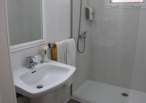La salle de bains blanche est pourvue d'un lavabo et d'une douche. dans l'établissement HOVIMA Panorama, à Adeje