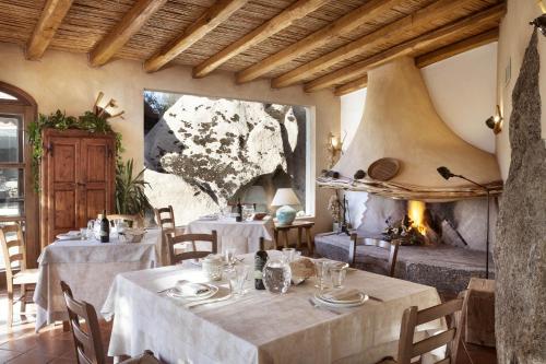 a dining room with two tables and a fireplace at Tenuta Pilastru Country Resort & Spa in Arzachena