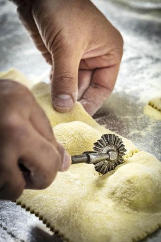a person cutting a piece of dough with a tool at Tenuta Pilastru Country Resort & Spa in Arzachena