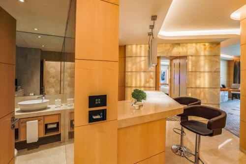 a kitchen with a sink and a counter with a stool at The Meydan Hotel Dubai in Dubai