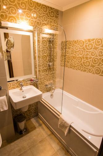 a bathroom with a tub and a sink and a shower at Hotel Balada in Suceava