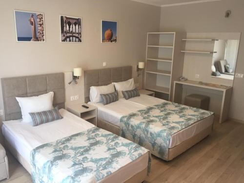 a hotel room with two beds and a shelf at Helios Hotel in Balchik