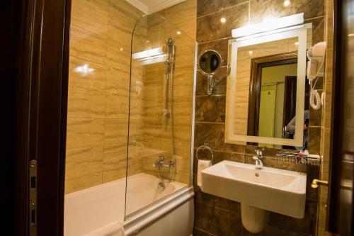 a bathroom with a shower and a sink and a tub at Hotel Balada in Suceava