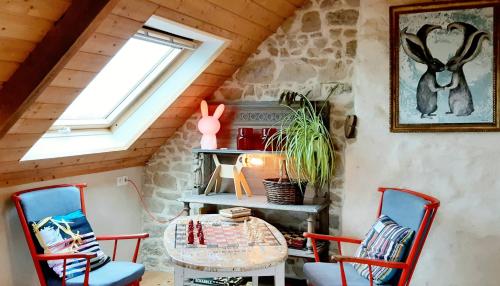 ein Zimmer mit einem Tisch und Stühlen im Dachgeschoss in der Unterkunft La grange aux lièvres, gîtes Kerdoel in Cléder