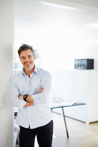 a man standing in an office with his arms crossed at Premiere Classe Beaune in Beaune