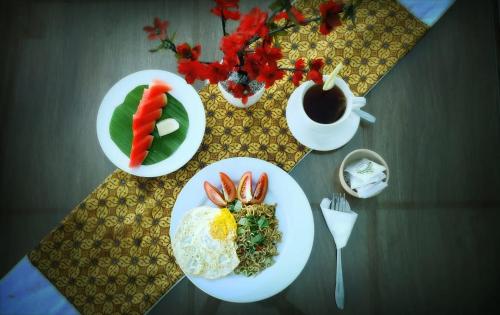 a table with plates of food and a cup of coffee at Alia Home in Sanur