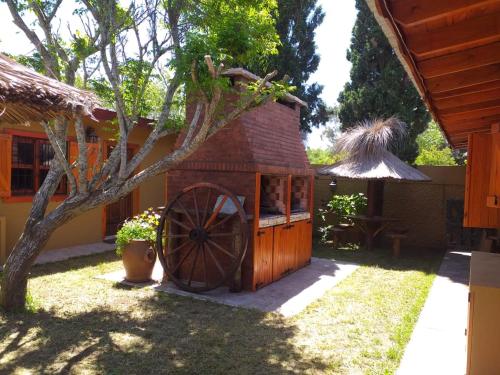 una pequeña casa con una rueda grande en el patio en EL REMANSO en Mar de Ajó