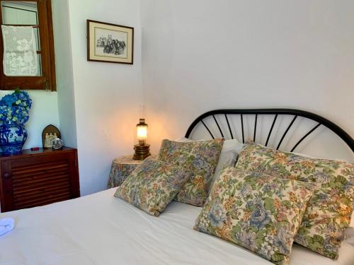 una camera da letto con letto bianco, cuscini e lampada di Stone House - Sete Cidades a Sete Cidades