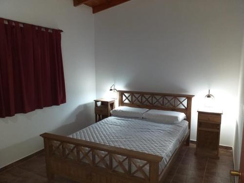 1 dormitorio con cama de madera y cortina roja en LOS SAUCES en Mar de Ajó