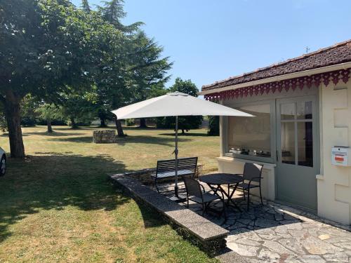 a table and chairs under an umbrella next to a house at Le Pontet in Miramont-de-Guyenne