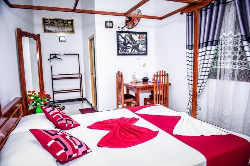 Yala New Nehansa Resort في تيساماهاراما: غرفة نوم بسرير ومخدات حمراء وطاولة