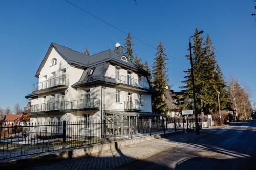 une grande maison blanche avec une clôture devant elle dans l'établissement Narciarski Dworek, à Zakopane