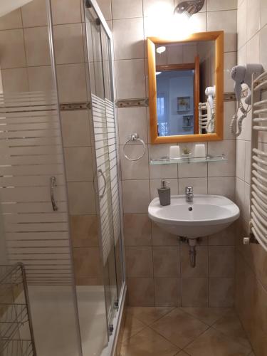 a bathroom with a sink and a shower with a mirror at Napsugár Vendégház in Kiskőrös