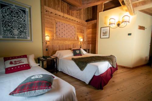 1 dormitorio con 2 camas en una habitación con paredes de madera en Laghetto Alpine Hotel & Restaurant, en Brusson