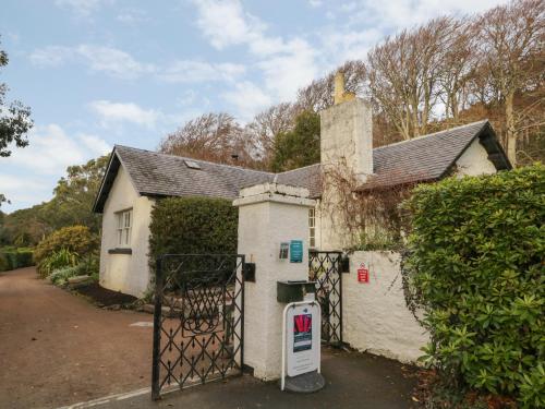 a white house with a gate in front of it at Inverewe - Garden Lodge in Achnasheen