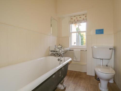 a bathroom with a tub and a toilet and a window at Cormack Lodge - Brodie Castle in Forres