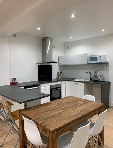 - une cuisine avec une table en bois et des chaises blanches dans l'établissement Bel appartement AVIGNON CENTRE, à Avignon