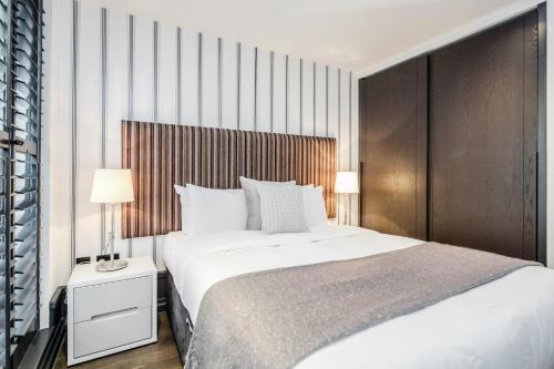 a bedroom with a large bed and a wooden wall at Stay Kula London - Covent Garden Garrick St in London