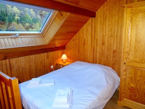 uma cama num quarto de madeira com uma janela em Les Oulles em La Chapelle-en-Valgodemard