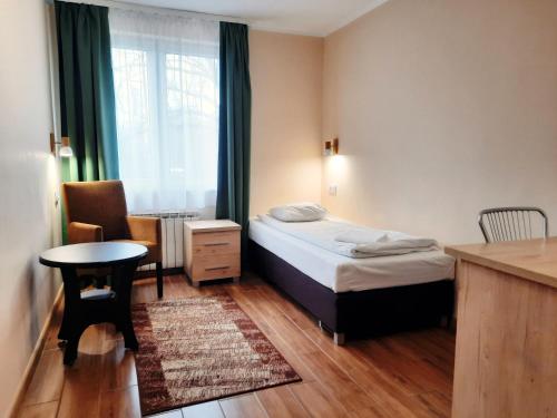 1 dormitorio con 1 cama, 1 mesa y 1 silla en Zajazd Wrota Lasu, en Hajnówka