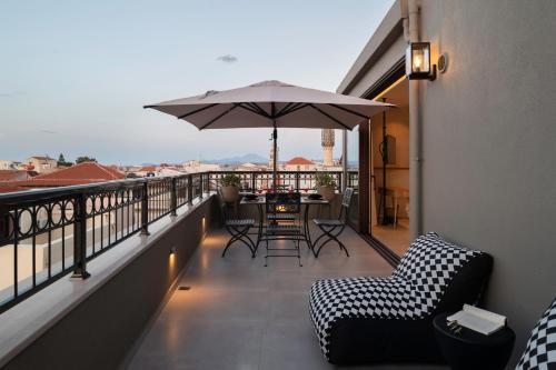 a balcony with a table and an umbrella at Petalo Suites in Rethymno Town