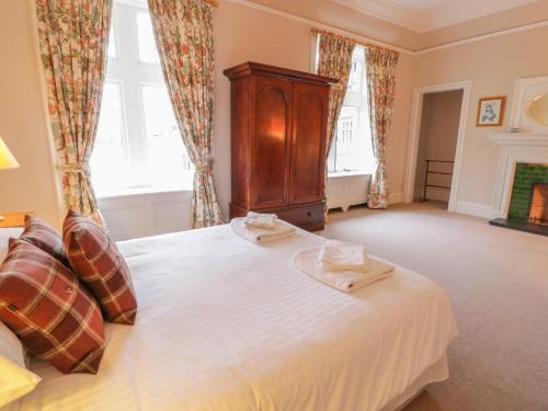 a bedroom with a bed with a wooden cabinet and windows at Bynack - Mar Lodge Estate in Ballater