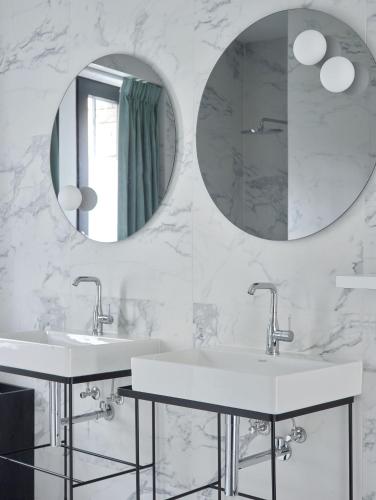 a bathroom with two sinks and two mirrors at Amosa Liège City Centre Hotel in Liège