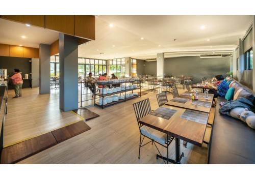 a restaurant with tables and chairs and people eating at The Wind Hotel in Bang Sare