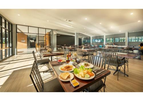 a restaurant with tables and chairs with food on them at The Wind Hotel in Bang Sare