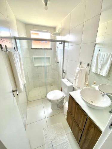 a white bathroom with a toilet and a sink at Condomínio Villa das Aguas com wi-fi in Praia do Saco
