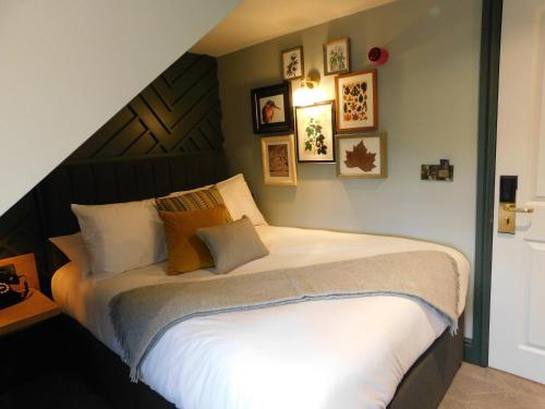 a bedroom with a large white bed with pictures on the wall at City Gate in Exeter