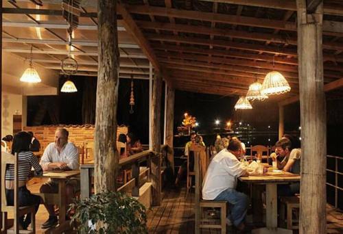 un grupo de personas sentadas en mesas en un restaurante en Pousada Rio Nilo, en Nilo Peçanha