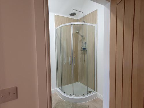 a shower with a glass door in a bathroom at 2-Bed Barn Hot Tub & Pet Friendly near Muirkirk in Cumnock
