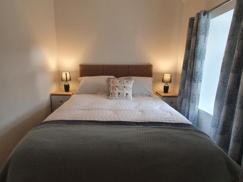 1 dormitorio con 1 cama con 2 lámparas y una ventana en Inviting 2-Bed Barn with hot tub near Muirkirk, en Cumnock