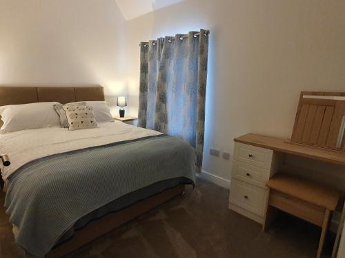 ein Schlafzimmer mit einem Bett, einer Kommode und einem Fenster in der Unterkunft 2-Bed Barn Hot Tub & Pet Friendly near Muirkirk in Cumnock