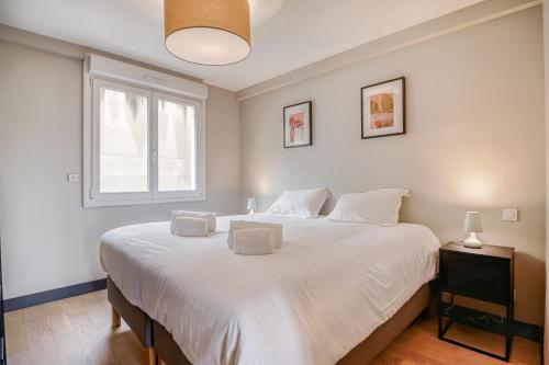 a bedroom with a large white bed with a window at Le Gambetta - T3 Standing avec Parking, Wifi, Netflix in Laval