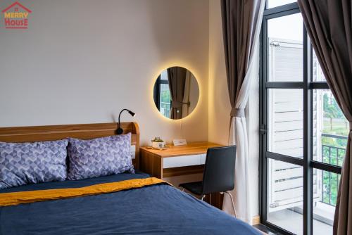 a bedroom with a bed and a desk and a mirror at Merry House Imperia in Hai Phong