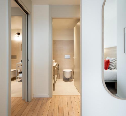 a bathroom with a toilet and a mirror at Apartahotel Líbere Vitoria in Vitoria-Gasteiz
