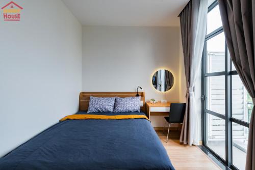 a bedroom with a bed and a desk and a window at Merry House Imperia in Hai Phong