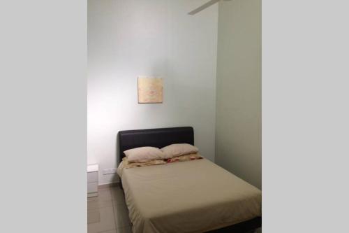 małe łóżko w pokoju z białymi ścianami w obiekcie Homestay Ayi w mieście Ayer Keroh