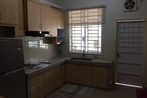 a kitchen with white cabinets and a sink and a window at Homestay Ayi in Ayer Keroh