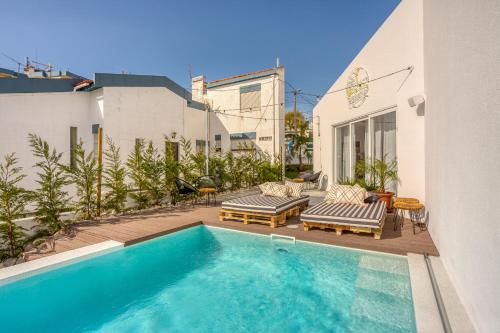 a swimming pool with two chaise lounges next to a building at Selina Boavista Ericeira in Ericeira