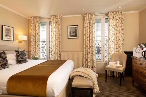 een slaapkamer met een bed, een stoel en ramen bij Hotel Relais Bosquet by Malone in Parijs