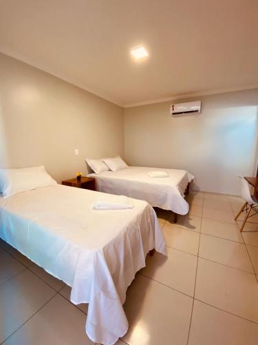 a hotel room with two beds and a chair at Bella Spiaggia Suítes in Flecheiras