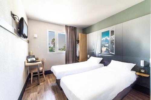 una camera d'albergo con 2 letti e una scrivania di B&B HOTEL Perpignan Saleilles a Perpignano