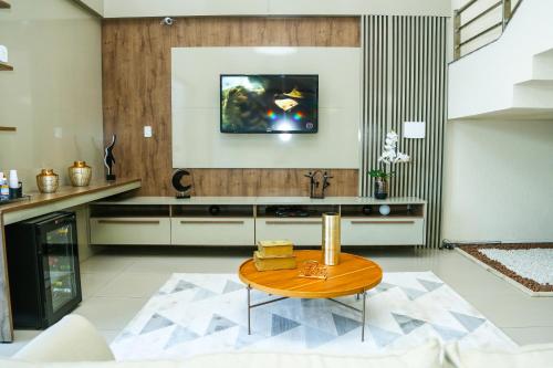a living room with a table and a tv on the wall at Avelan Plaza Hotel in Nossa Senhora da Glória