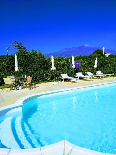 a swimming pool with chairs and umbrellas next to at Case Vacanze Residence Trinacria in Acireale